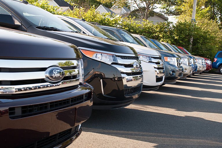 A row of Ford SUVs is parked side by side at a dealership.