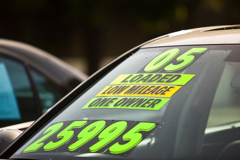 Used vehicle A close-up of a car's windshield shows several fluorescent green and yellow stickers with 