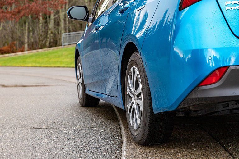A low-angle, rear view of a blue Toyota Prius on a driveway.