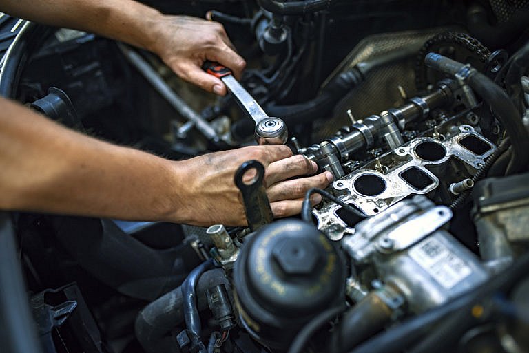 Mechanic working on an engine of a Kia vehicle.