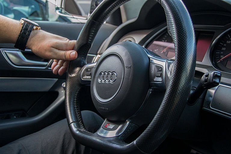 A person's hand holding the steering wheel inside an Audi.