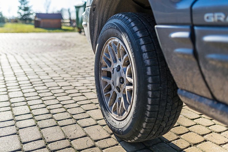 Close-up of a Jeep tire and alloy wheel on a stone driveway.