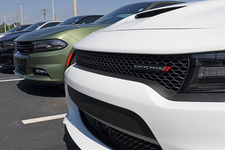 A row of Dodge Charger cars is parked in a lot.