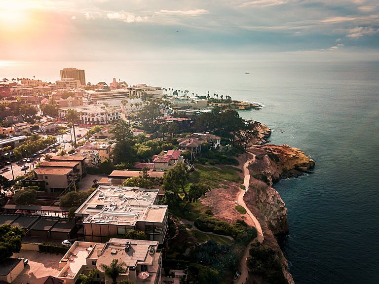 Aerial view of coastal homes and cliffs overlooking the ocean at sunset
