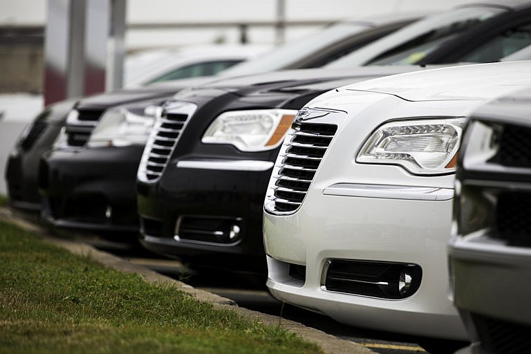 A row of Chrysler 300 sedans is parked at a dealership.