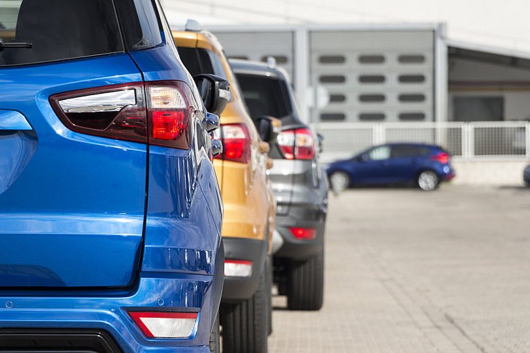 A row of Ford SUVs in blue, yellow, and gray are lined up.