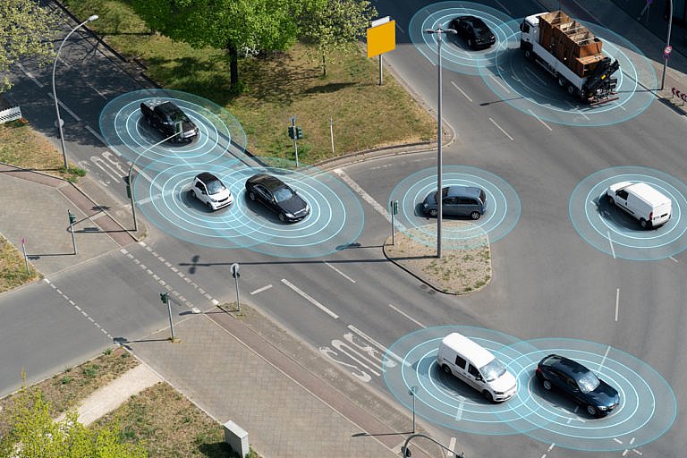 An aerial view of an intersection showing several cars, each with a blue glowing circle around it.