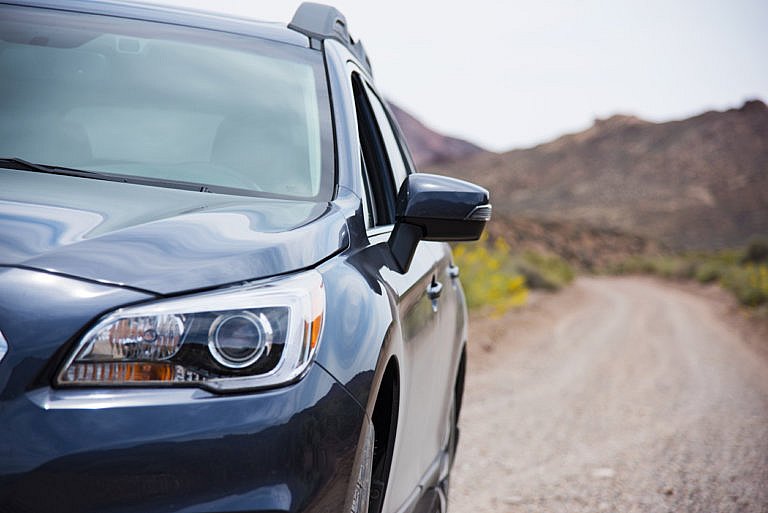 A Subaru SUV parked on a dirt road near the mountains.