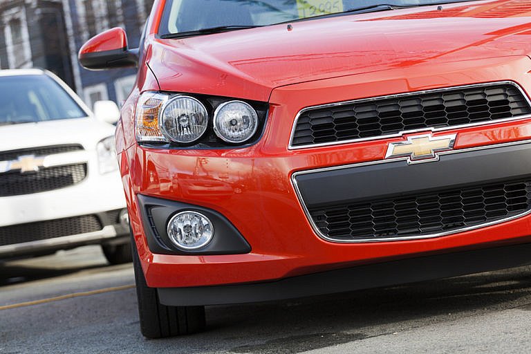 Red Chevrolet car parked with a white Chevrolet in the background.