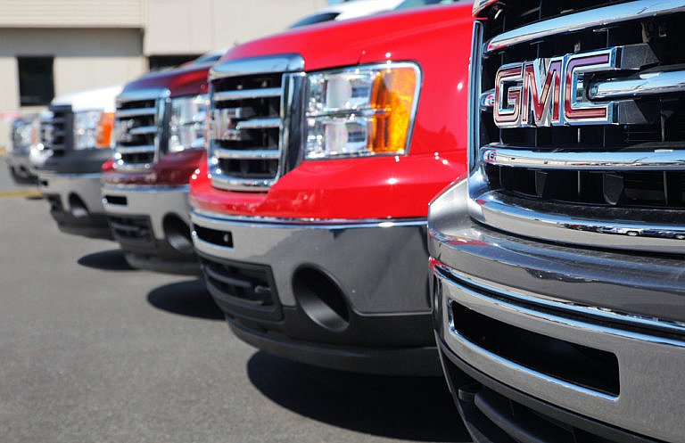 Row of GMC trucks parked at a dealership lot.