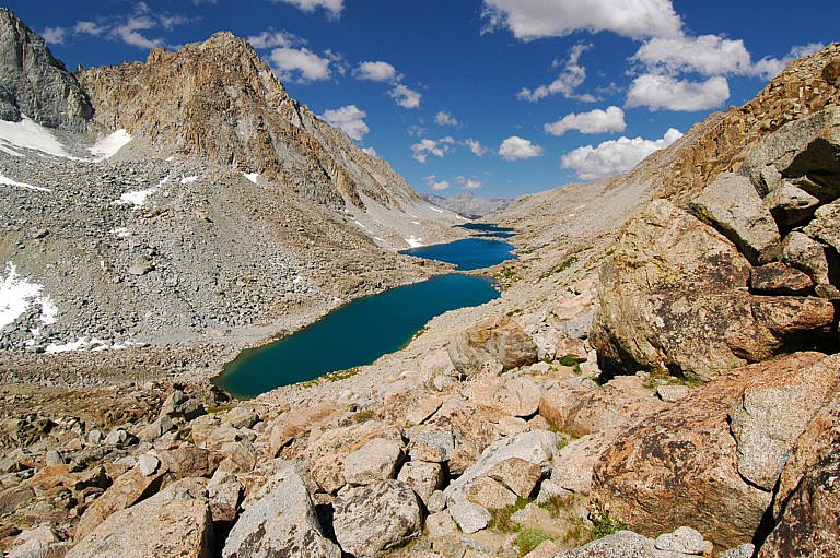 Alpine lake surrounded by rocky mountains under a bright blue sky with clouds