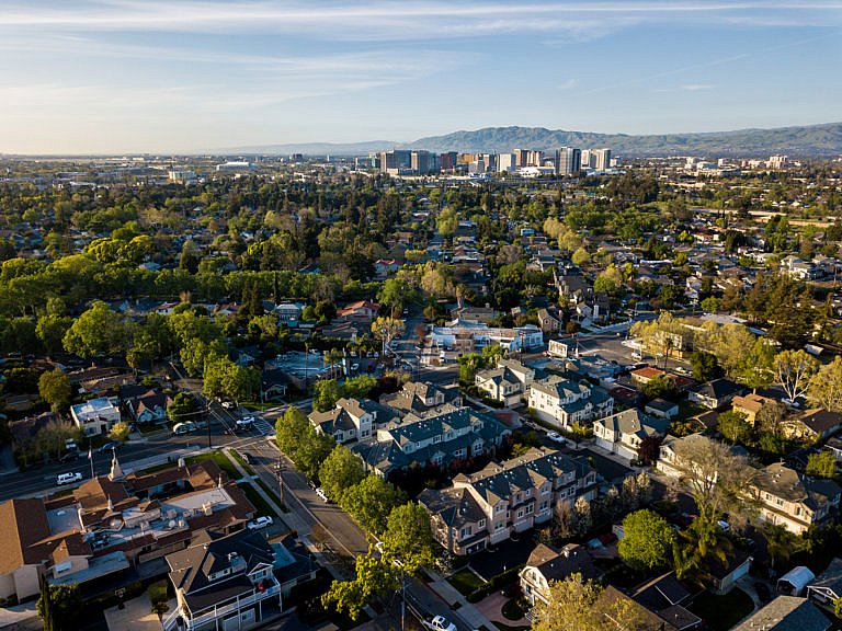Aerial view of suburban neighborhood with city skyline and mountains in the background