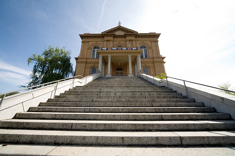 Wide stone steps lead up to a historic courthouse with columns and a triangular pediment.