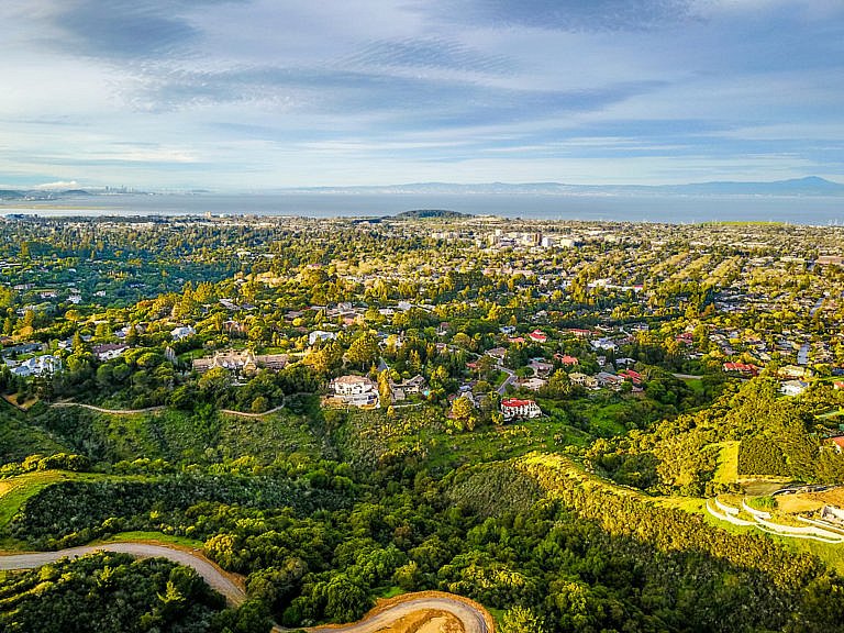 Aerial view of Palo Alto with green hills and San Francisco Bay in the distance.
