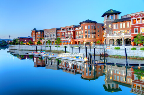 Colorful waterfront buildings reflected in calm blue water at dusk.