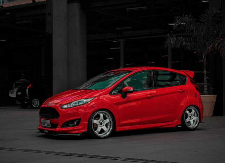 A red Ford Fiesta hatchback is parked in front of a building.