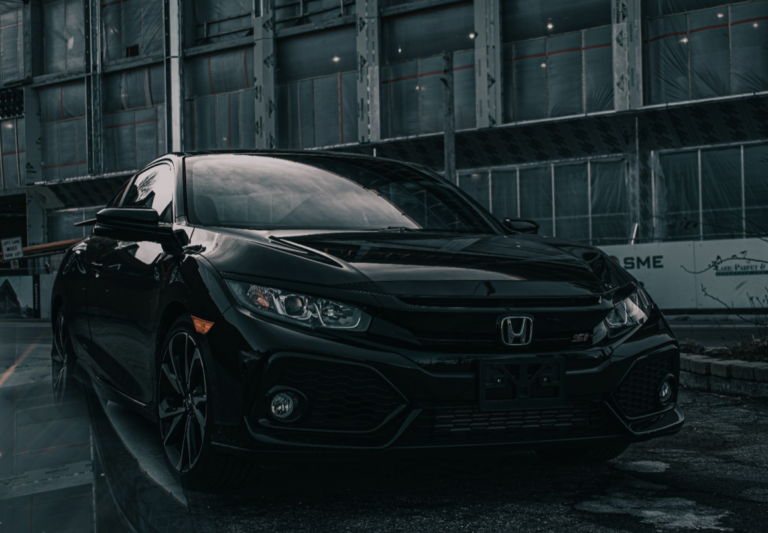 A sleek black Honda Civic Si is parked dramatically against an industrial background in the Philippines.