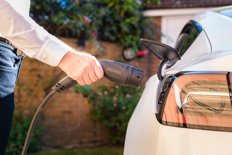 A man plugging in a charging cable to an electric car.