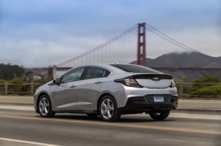 A silver Chevrolet Volt is driving on a highway with the Golden Gate Bridge in the background.