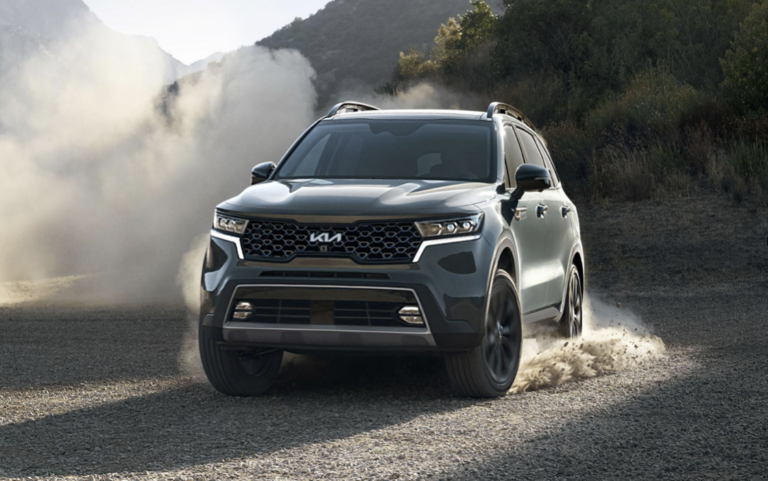 A Kia Sorento SUV on a dirt road kicking up dust.