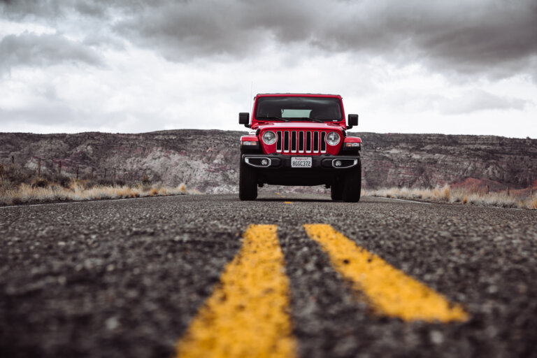 Red Jeep Wrangler facing forward on an empty road.