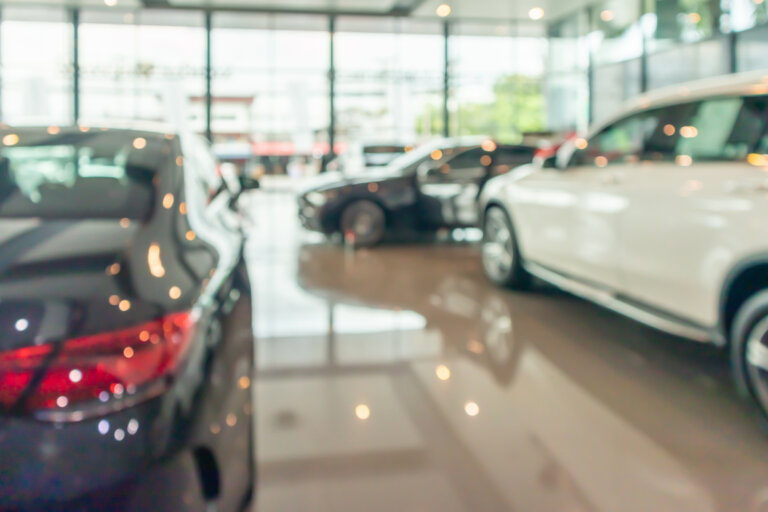 Blurred view of cars displayed inside a modern showroom