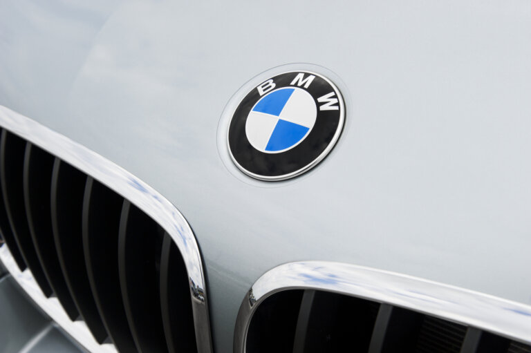 A close-up of a BMW's hood shows the circular logo and a portion of the chrome grille.
