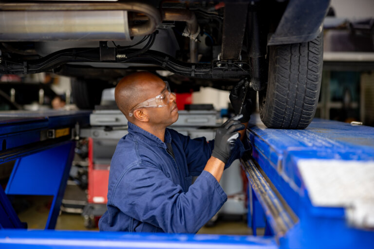 mechanic inspects a vehicle’s suspension on a lift.