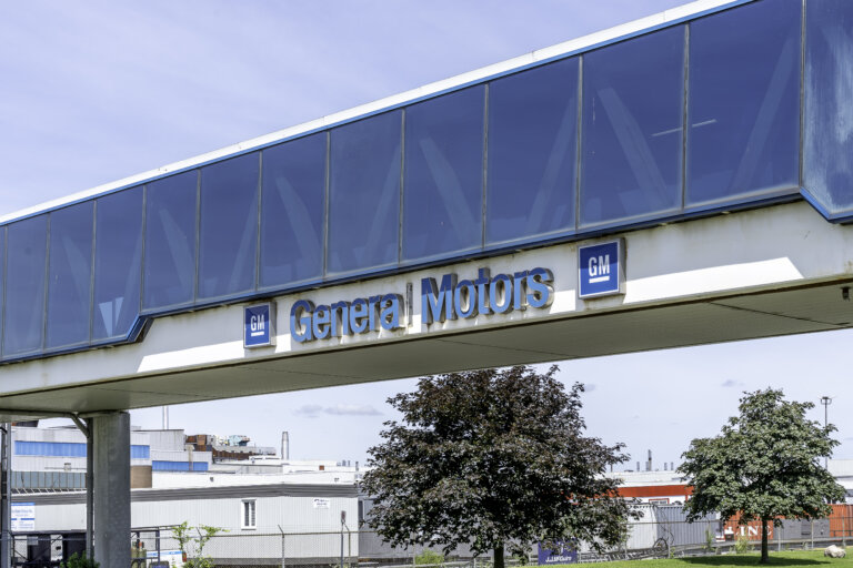General Motors logo and signage on a walkway bridge at an industrial facility.