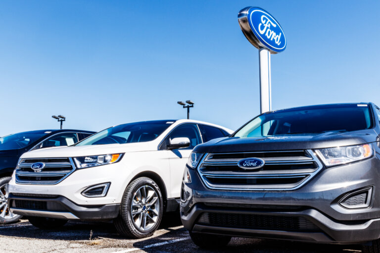 A row of Ford SUVs is parked under a dealership sign.