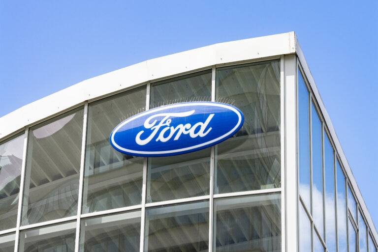 A Ford logo sign mounted on a glass dealership building.