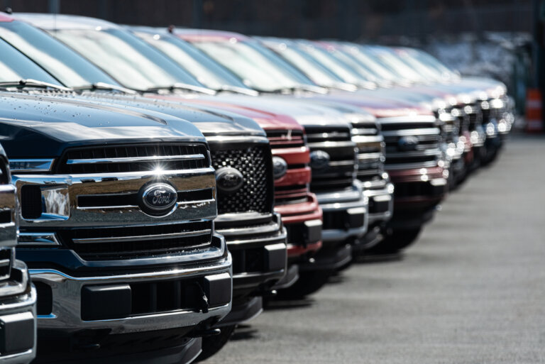 A row of Ford pickup trucks is lined up at a dealership lot.