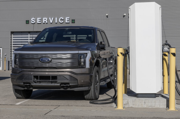 A Ford F-150 Lightning is charging at a service station.