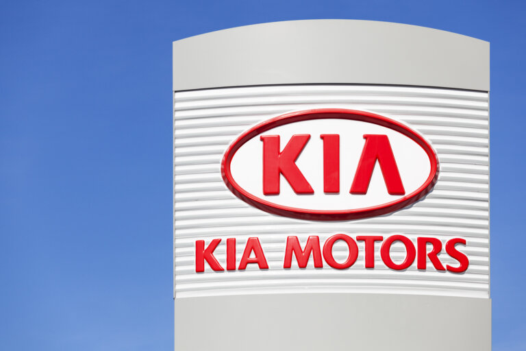 A sign for a Kia Motors dealership against a blue sky.
