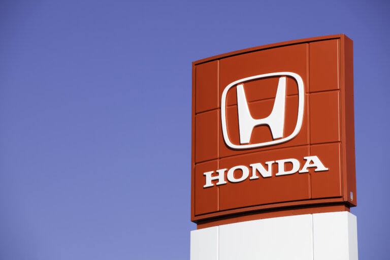 A prominent red Honda sign with its white logo stands tall against a clear blue sky.