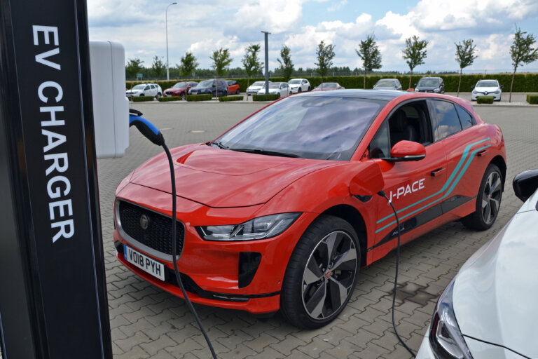 Red Jaguar I-PACE electric SUV charging at an EV station