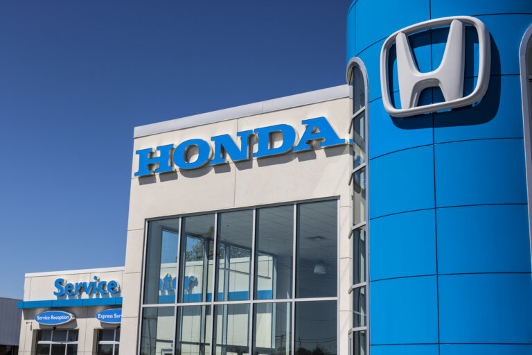 A clear, sunny day highlights the Honda dealership building and its prominent blue logo.