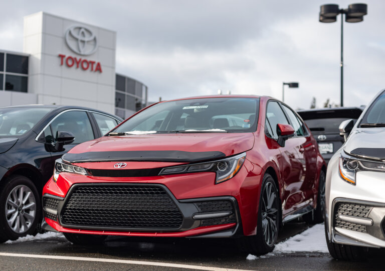 A red Toyota sedan parked outside a Toyota dealership.
