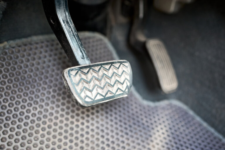 Close-up of a worn brake pedal inside a car