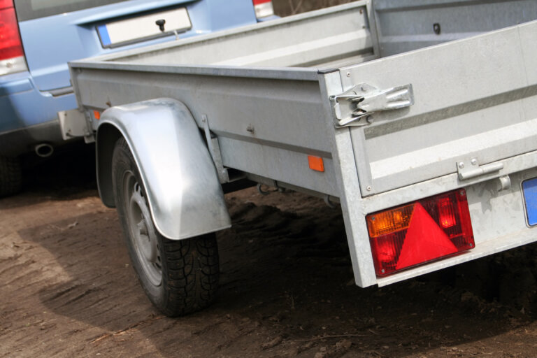 Small metal utility trailer attached to a blue vehicle