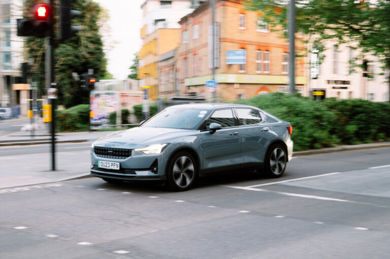 Grey Polestar 2 driving through city streets at a red light.