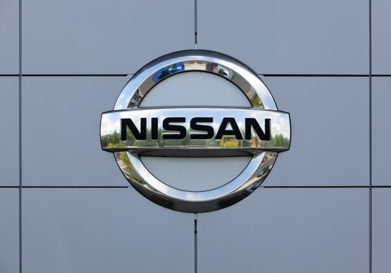 The chrome Nissan logo emblem mounted on the grey paneled wall of a building.