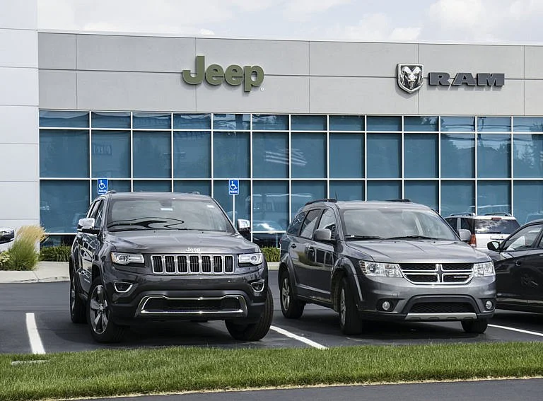 Jeep and Dodge SUVs parked in front of a dealership building.