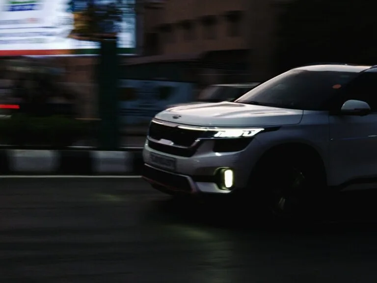 White Kia SUV driving on a city street